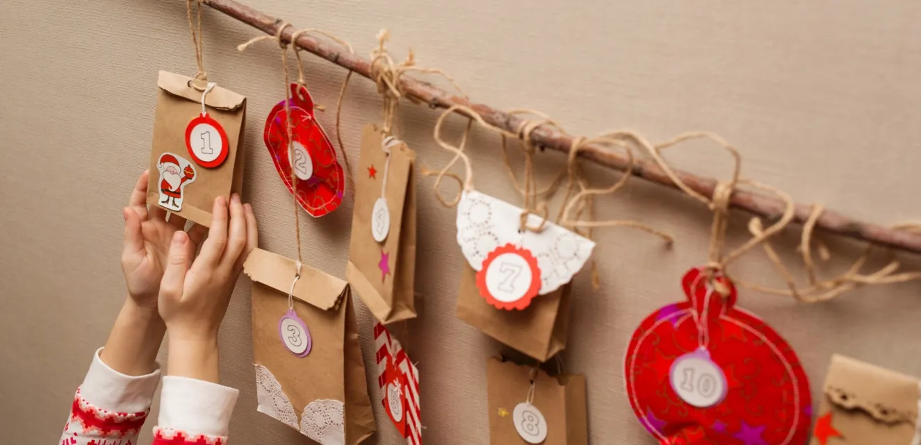 An image of lots of envelopes handing from string being used as an advent calendar with a child holding one of the envelopes.